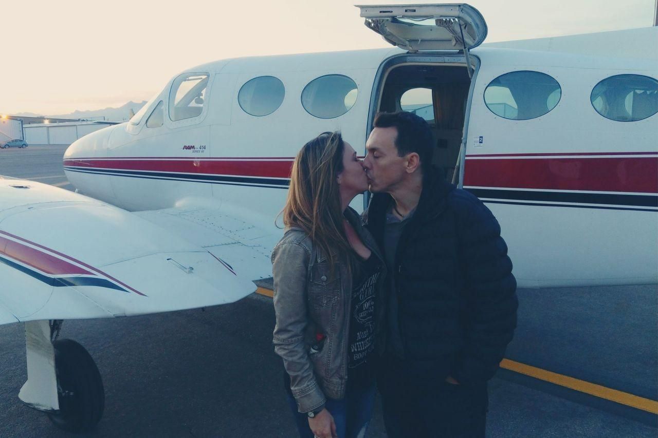 A couple kissing in front of a private plane