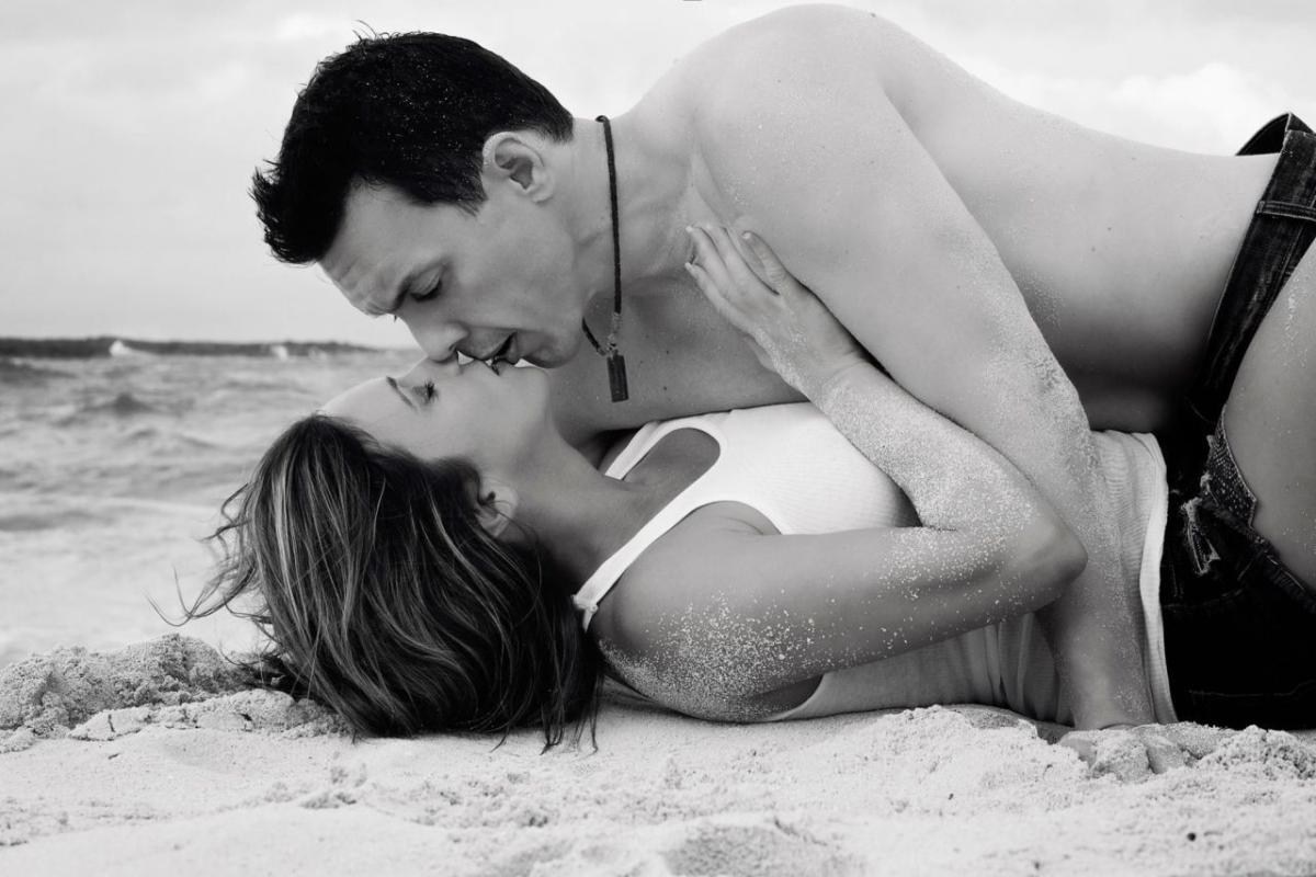 A couple laying on the beach kissing